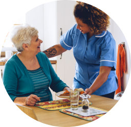 a female caregiver serving an elderly woman