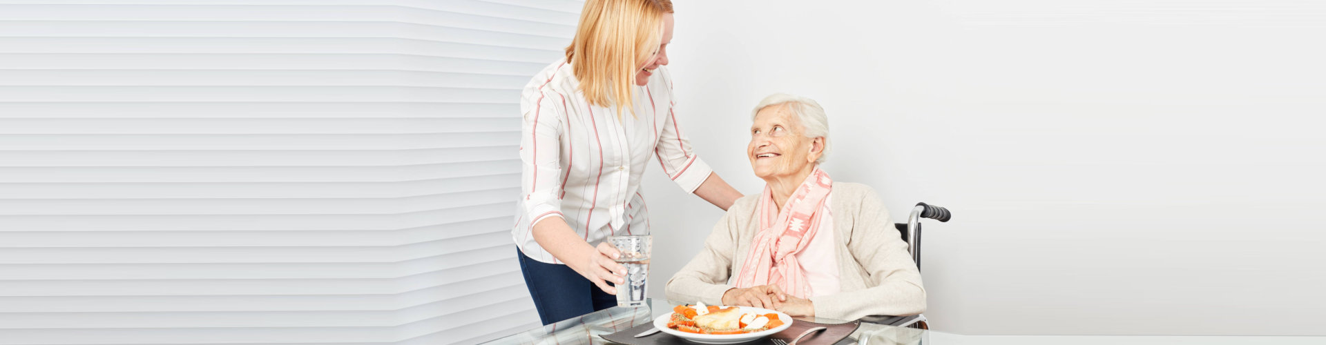a caregiver giving meal to the senior woman